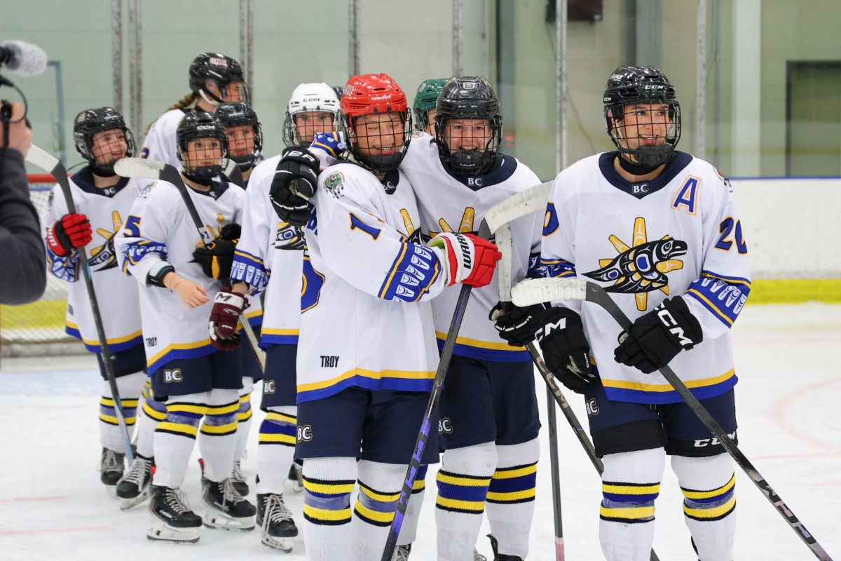 L'équipe de la Colombie-Britannique est sur la glace, vêtue de chandails blancs. Les jeunes joueurs sourient.